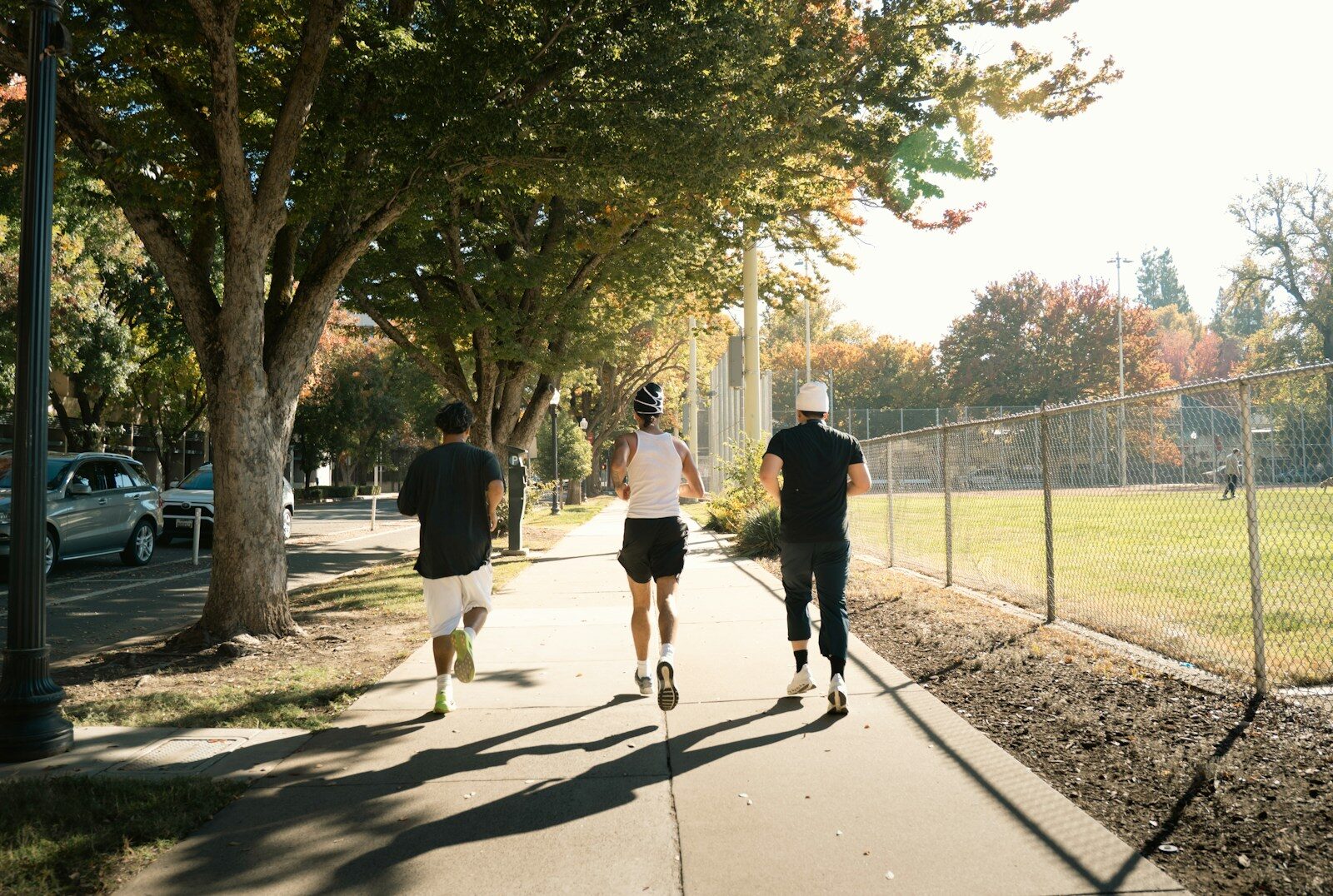 Three people jogging on a sunny sidewalk